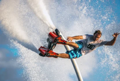 A detailed close-up shot of a rider performing a trick, showing the red Zapata Flyboard® and water nozzles in action.