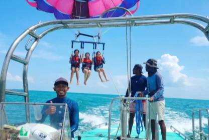 Three people enjoying a tandem parasailing flight above the sea in Bali